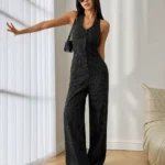 Black Pinstripe Wide Leg Jumpsuit by ELYRA LABEL featuring a sleeveless V-neck design, front button closure, tailored fit, and elegant wide-leg silhouette