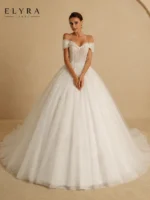 Princess Ball Gown Wedding Dress by ELYRA LABEL featuring an off-shoulder sweetheart neckline, glitter embroidered organza and tulle, appliqué beading, lace-up back, and elegant floor-length ball gown silhouette.